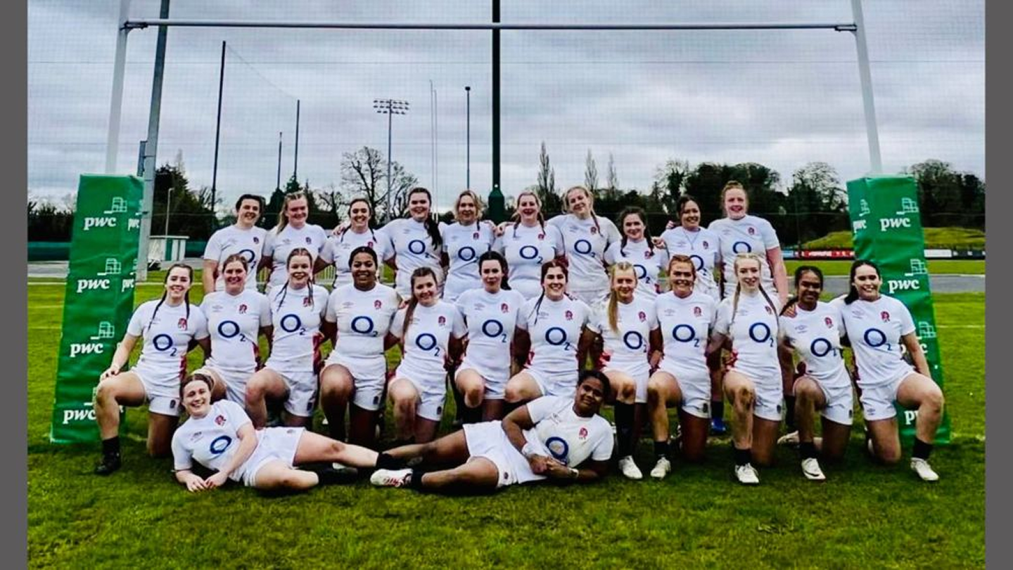Group photo of Womens Rugby team in front of goal posts